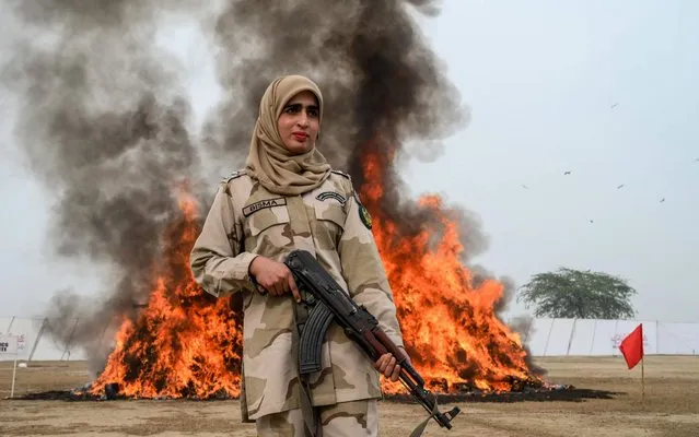 A soldier from Pakistan's Anti-Narcotics Force (ANF) stands beside a burning pile of seized drugs set on fire during a drug burning ceremony in Lahore on December 11, 2019. (Photo by Arif Ali/AFP Photo)