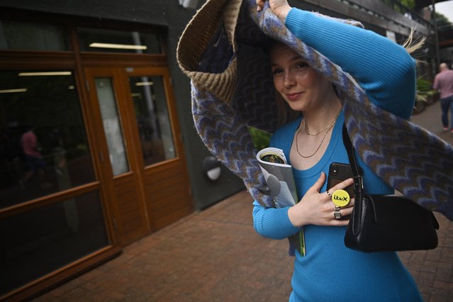 A spectator covers their head as it rains on the first day of Wimbledon at All England Lawn Tennis and Croquet Club in London, Britain on July 3, 2023. (Photo by Dylan Martinez/Reuters)