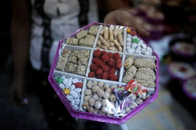 A worker holds a tray of packed traditional Chinese New Year snacks in a workshop in Yangon, Myanmar, January 20, 2020. (Photo by Ann Wang/Reuters)