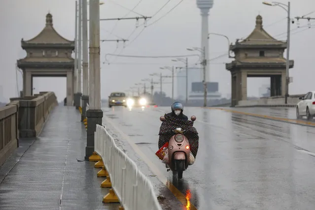 A motorcyclist rides across a bridge in Wuhan in central China's Hubei province, Saturday, January 25, 2020. The virus-hit Chinese city of Wuhan, already on lockdown, banned most vehicle use downtown and Hong Kong said it would close schools for two weeks as authorities scrambled Saturday to stop the spread of an illness that is known to have infected more than 1,200 people and killed 41, according to officials. (Photo by Chinatopix via AP Photo)