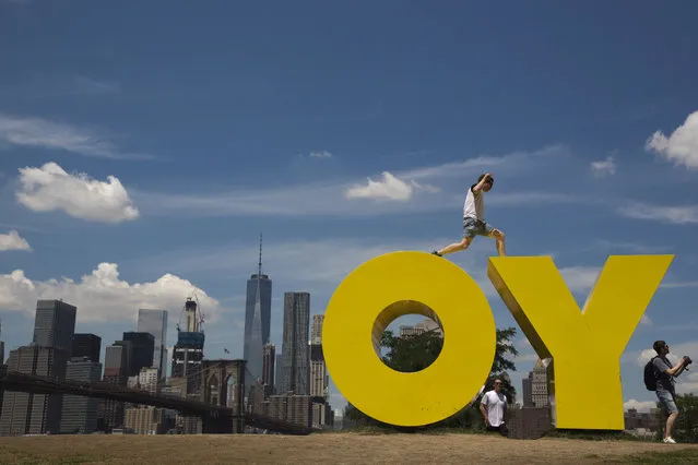 A visitor to the Brooklyn Bridge park jumps between the letters in Deborah Kass' sculpture OY/YO, Thursday, June 30, 2016, in New York. (Photo by Mary Altaffer/AP Photo)