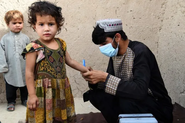 A health worker marks a child's finger with ink after giving polio vaccine at a campaign in Kandahar on June 28, 2022. (Photo by Javed Tanveer/AFP Photo)