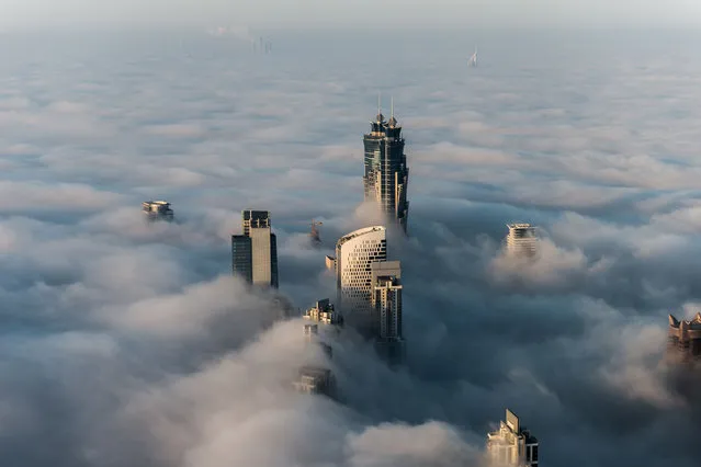 This breathtaking view from the world's tallest building shows a thick blanket of smoggy fog smother Dubai. The mist almost completely covers the huge sculptures which dominate the skyline. And the spectacular view from the Burj Khalifa – standing at a staggering 828 metres tall – shows the city engulfed by the thick fog. And the smoggy fog reaches heights of up to 400 metres as it rises above the impressive skyscrapers in Dubai. (Photo by Bjoern Lauen/Solent News/SIPA Press)