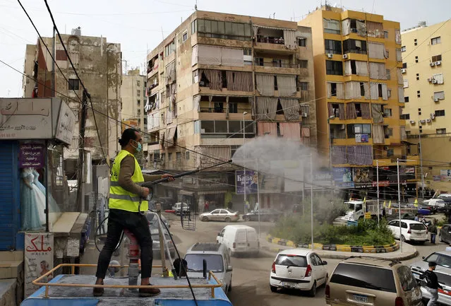 A municipal worker sprays disinfectant as a precaution against the coronavirus outbreak, in the southern suburb of Beirut, Lebanon, Friday, March 27, 2020. (Photo by Bilal Hussein/AP Photo)