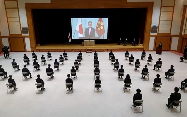 New employees of Japan's defence ministry sit on chairs spaced apart for social distancing due to concerns over the spread of COVID-19 coronavirus, as they watch a video message of Defence Minister Taro Kono during a ceremony in Tokyo on April 1, 2020. (Photo by JIJI Press/AFP Photo)