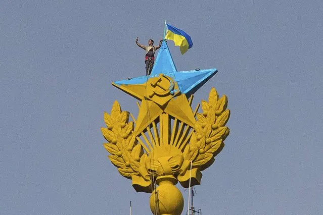 A man takes a “selfie” as he stands with a Ukrainian flag on a Soviet-style star re-touched with blue paint so it resembles the yellow-and-blue national colours of Ukraine, atop the spire of a building in Moscow August 20, 2014. Russian police said on Wednesday they had charged four young people with vandalism after they climbed to the top of a Moscow skyscraper and briefly attached a Ukrainian flag to its spire. (Photo by Ilya Varlamov/Reuters)