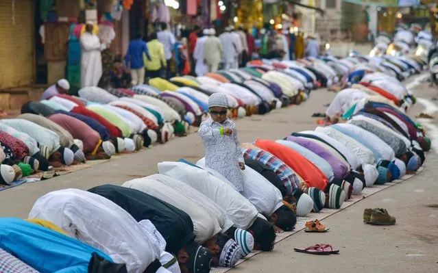A child looks at his watch as Muslims pray during Eid al-Adha in Ajmer in the western Indian state of Rajasthan on August 12, 2019. Muslims around the world are celebrating Eid al-Adha (the feast of sacrifice), the second of two Islamic holidays celebrated worldwide marking the end of the annual pilgrimage or Hajj to the Saudi holy city of Mecca. (Photo by Shaukat Ahmed/AFP Photo)