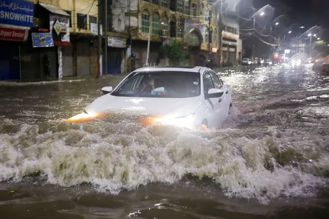 A vehicle drives along a flooded street, following heavy rains during the monsoon season in Karachi, Pakistan on July 24, 2022. (Photo by Akhtar Soomro/Reuters)