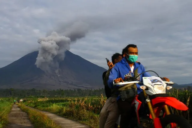 Villagers ride a motorcycle as Mount Semeru volcano spews ash and smoke in Supiturang village, Lumajang, East Java province, Indonesia, December 7, 2021. (Photo by Ari Bowo Sucipto/Antara Foto via Reuters)