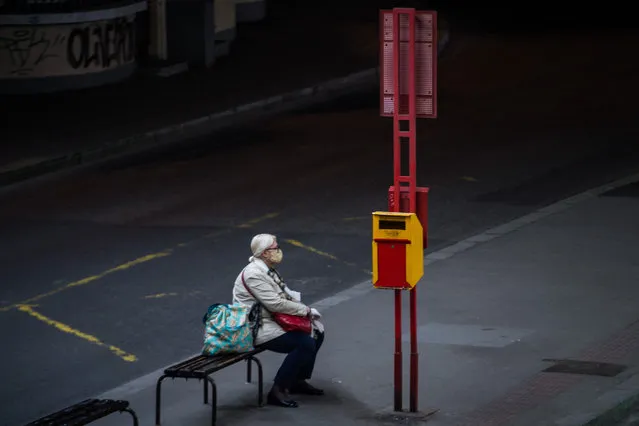 A woman wearing a face mask waits at the bus stop under the New Bridge in Bratislava, Slovakia on April 20, 2020, amid the novel coronavirus COVID-19 pandemic. (Photo by Vladimir Simicek/AFP Photo)