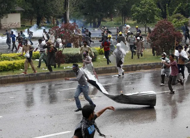 Anti-government protesters carry sticks as they run to put up a blockade along the road during the Revolution March towards the Prime Minister's house in Islamabad September 1, 2014. Pakistan is preparing to launch a selective crackdown against anti-government protesters trying to bring down the government of Prime Minister Nawaz Sharif, the defense minister said, warning demonstrators against storming government buildings. (Photo by Akhtar Soomro/Reuters)