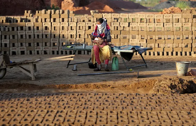 An Indian woman laborer feeds her child at a brick kiln after resuming work during lockdown on the outskirts of Jammu, India, Wednesday, April 22, 2020. India has reported nearly 20,000 confirmed cases of COVID-19 and over 600 deaths. (Photo by Channi Anand/AP Photo)