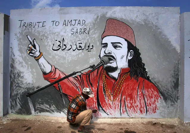 A Pakistani painter gives final touches to a mural of slain Sufi singer Amjad Sabri to pay homage to him, in Karachi, Pakistan, Tuesday, June 28, 2016. Sabri, a well-known Pakistani Sufi singer who was shot dead in the port city of Karachi in an attack on last week claimed by Islamic extremists. (Photo by Shakil Adil/AP Photo)