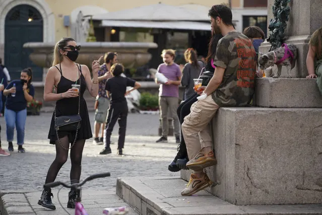 People enjoy a drink in Rome's fashionable Campo De' Fiori Square, as the city is slowly returning to life after the long shutdown due to the coronavirus outbreak, Friday, May 8, 2020. (Photo by Andrew Medichini/AP Photo)