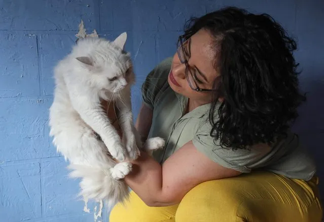Amal Amro, the Palestinian-Syrian owner, plays with a cat at 'Amal Pets Hotel' in Arbil, the capital of Iraq's northern Kurdish autonomous region, on August 24, 2022. (Photo by Safin Hamed/AFP Photo)
