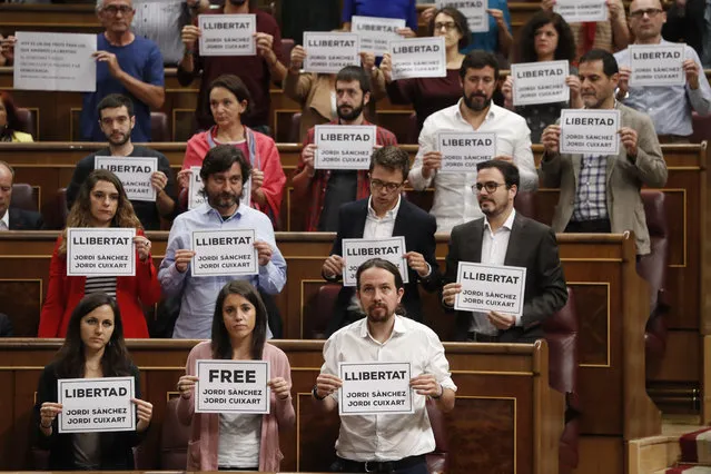 Unidos Podemos MPs hold banners in support of pro-independence leaders from Catalonian National Assembly, Jordi Sanchez, and Omnium Cultural, Jordi Cuixart, imprisoned two days ago for a sedition offense, during Question Time at the Lower House in Madrid, Spain, 18 October 2017. (Photo by Javier Lizon/EPA/EFE)