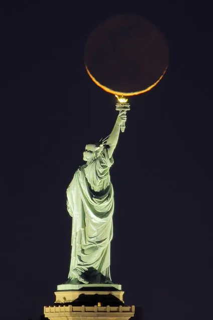 A 2.5 percent waning gibbous moon illuminated with earthshine rises behind the Statue of Liberty before sunrise in New York City on September 24, 2022, as seen from Jersey City, New Jersey. (Photo by Gary Hershorn/Getty Images)