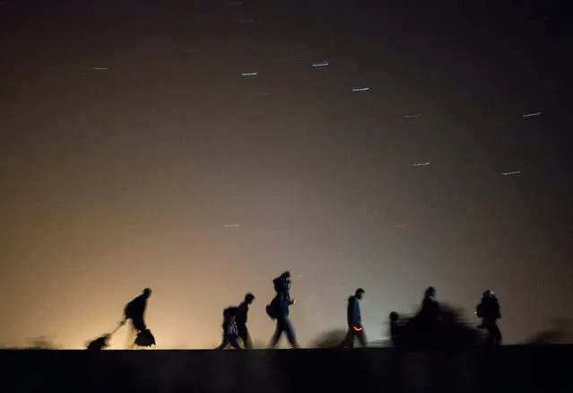 In this September 13, 2015 photo taken with slow shutter speed migrants walk towards a checkpoint along the railway tracks connecting Horgos and Szeged near Roszke, in the vicinity of the border between Hungary and Serbia. (Photo by Balazs Mohai/MTI via AP Photo)