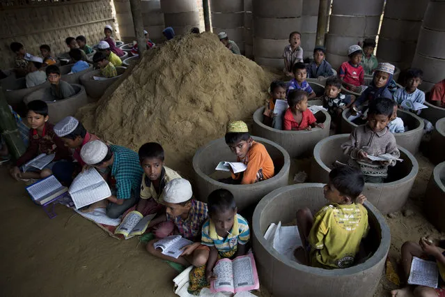 Rohingya refugee children attend recitation classes of the holy Quran in a newly opened madrasa, or religious school, amid material stocked for constructing latrines in Balukhali refugee camp, Bangladesh, Monday, October 30, 2017. More than 600,000 Rohingya from northern Rakhine state have fled to Bangladesh since Aug. 25, when Myanmar security forces began a scorched-earth campaign against Rohingya villages. (Photo by Bernat Armangue/AP Photo)