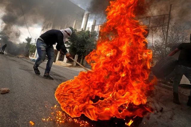 A demonstrator moves a burning tire during an anti-Israel protest following the funeral of Palestinian man Ibraheem Yakoub, in Kifl Haris in the Israeli-occupied West Bank July 10, 2020. (Photo by Mohamad Torokman/Reuters)