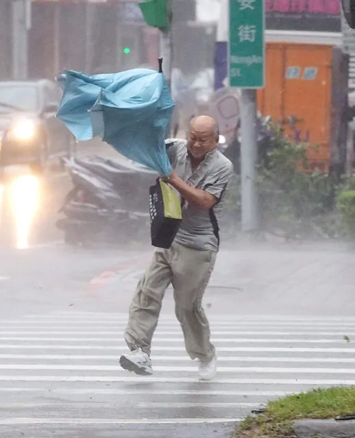 A man struggles with his umbrella as he crosses a street in Taipei, Taiwan, 28 September 2015 as Typhoon Dujuan slams Taiwan. Dujuan, called a strong tyhoon by the Central Weather Bureau, landed on Taiwan's east coast Monday afternoon, bringing strong wind and heavy rain and disrupting land and air traffic. Dujuan will pass Taiwan Monday night on its way to China. (Photo by David Chang/EPA)