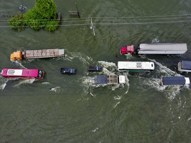 In this aerial view vehicles drive along the flooded Jujan Babahoyo road following heavy rains in Jujan, Guayas province, Ecuador, on March 12, 2025. According to official reports, since January, the rains have left at least 19 dead and affected more than 100,000 people in the South American country. (Photo by Marcos Pin/AFP Photo)
