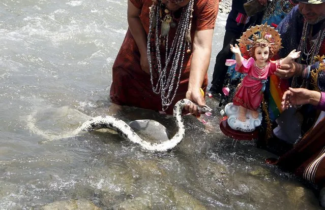 Peruvian shamans, holding a figure of Nino Jesus (Child Jesus) and a snake, perform a ritual at the Rimac river to fight the negative effects of the Nino weather phenomena over Nature, in Lima, October 1, 2015. (Photo by Mariana Bazo/Reuters)
