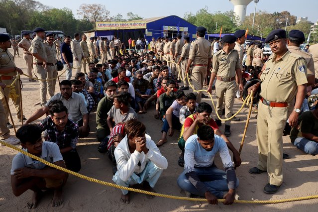 Police officers stand next to men they believe to be undocumented Bangladeshi nationals after they were detained during raids in Ahmedabad, India, on April 26, 2025. (Photo by Amit Dave/Reuters)