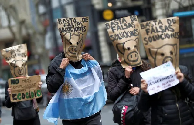 Demonstrators wearing paper bags with pigs drawn on them on their heads, march towards the Casa Rosada Presidential Palace in demand of a wetlands law and to protest against the agreement between Argentina and China to produce and export pork, in Buenos Aires, Argentina on August 25, 2020. (Photo by Agustin Marcarian/Reuters)