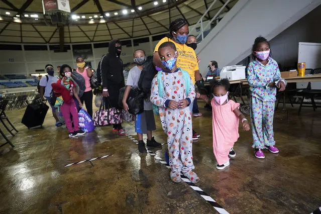 Victoria Nelson with her children Autum Nelson, 2, Shawn Nelson, 7, and Asia Nelson, 6, line up to board a bus to evacuate Lake Charles, La., Wednesday, August 26, 2020, ahead of Hurricane Laura. (Photo by Gerald Herbert/AP Photo)