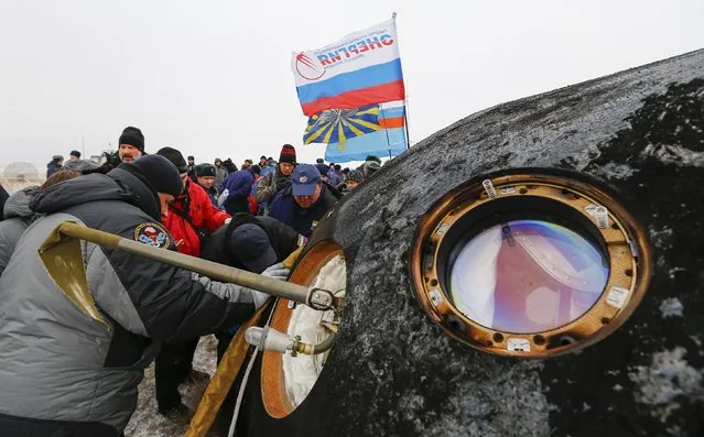 Ground personnel work next to the Soyuz TMA-13M capsule of the International Space Station (ISS) crew of Alexander Gerst of Germany, Maxim Suraev of Russia and Reid Wiseman of the U.S. after its landing near the town of Arkalyk in northern Kazakhstan November 10, 2014. (Photo by Shamil Zhumatov/Reuters)