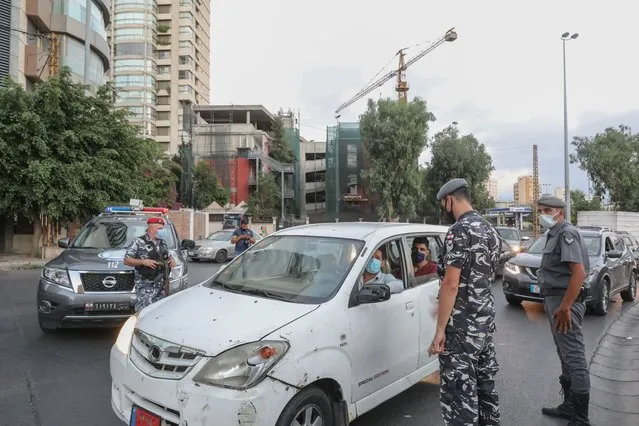 Members of the Lebanese security forces man a checkpoint on an avenue in the capital Beirut to verify the compliance with restrictions on the first day of a reinstated lockdown to combat a surge in COVID-19 cases, on August 21, 2020. Still reeling from a deadly port blast that ravaged many of its capital's homes and businesses, Lebanon wearily entered into a new coronavirus lockdown for two weeks as of August 21, to stem a string of record daily infection rates that have brought the number of COVID-19 cases to 11,580, including 116 deaths. (Photo by Anwar Amro/AFP Photo)