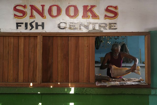 A fishmonger guts a fish at the Stabroek Market at the port of Georgetown, Guyana, November 19, 2024. (Photo by Matias Delacroix/AP Photo)
