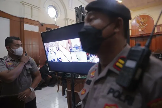 Police officers stand near a monitor inside a court room during a trial in Surabaya, East Java, Indonesia , Monday, January 16, 2023. The court began a trial Monday against five men on charges of negligence leading to deaths of 135 people after police fired tear gas inside a soccer stadium, setting off a panicked run for the exits in which many were crushed. (Photo by Trisnadi/AP Photo)