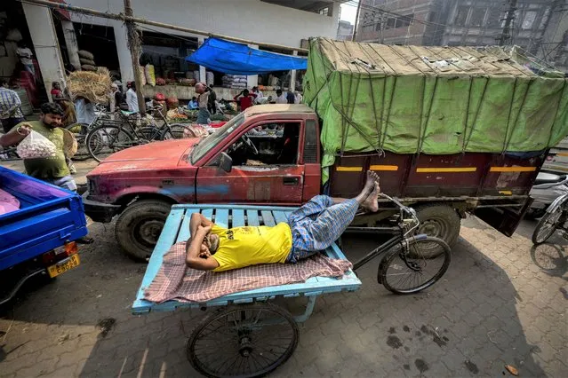 A man on a pushcart sleeps at a wholesale vegetable market in Guwahati, India, Wednesday, February 1, 2023. (Photo by Anupam Nath/AP Photo)