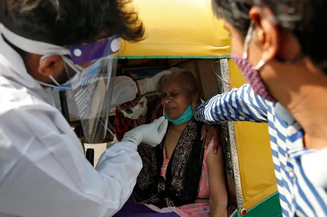 A woman sitting in an autorickshaw reacts as a healthcare worker takes a swab from her for a rapid antigen test in a street, amidst the coronavirus disease (COVID-19) outbreak, in Ahmedabad, India, October 5, 2020. (Photo by Amit Dave/Reuters)