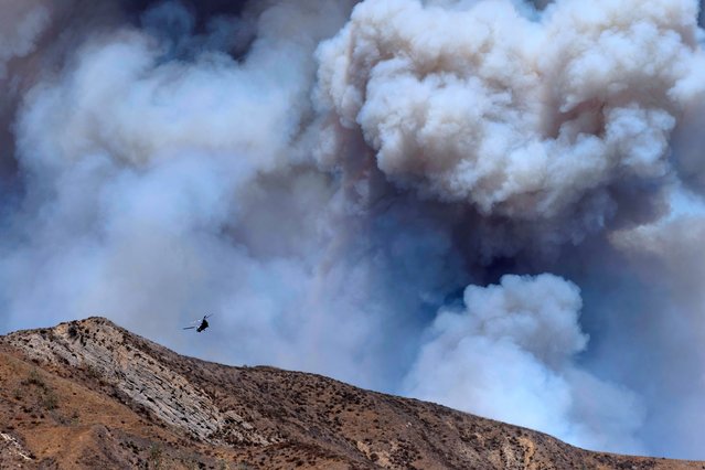 A helicopter drops water on smoke from the Canyon Fire on August 7, 2025 in Piru, California. Evacuation warnings have been issued from the L.A. County line to the northwest of Lake Piru. According to the National Weather Service, temperatures in the area reached between 90 to 100 degrees with 15% to 20% humidity. (Photo by Eric Thayer/Getty Images)