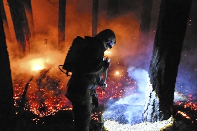 A Russian Emergency Situation ministry firefighter works to extinguish a wildfire near Atamanovka, in Transbaikal Territory in Zabaikalsky Krai of eastern Russia, Monday, June 23, 2025. (Photo by AP Photo/Stringer)