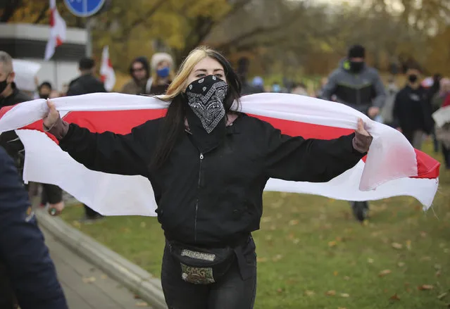 A woman holds an old Belarusian national flag during an opposition rally to protest the official presidential election results in Minsk, Belarus, Sunday, November 1, 2020. (Photo by AP Photo/Stringer)