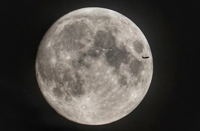 A plane passes the moon as it rises over Northumberland in north east England on July 16, 2019. (Photo by Owen Humphreys/PA Images via Getty Images)