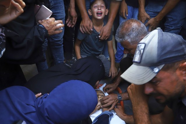 Palestinian relatives mourn over the body of 13-year-old Karim Qdeih, who was killed along with others in overnight Israeli strikes, during his funeral outside Nasser Hospital in Khan Younis, southern Gaza Strip, Saturday, August 23, 2025. (Photo by Mariam Dagga/AP Photo)