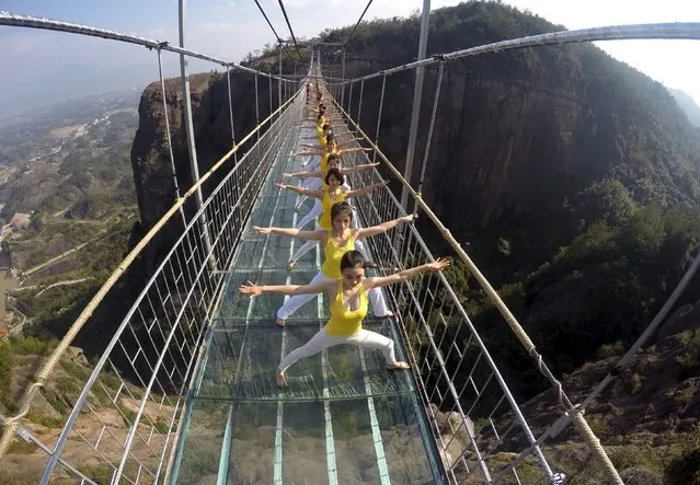 Women practice yoga during a performance on a glass bridge at the Shiniuzhai National Geo-park in Pingjiang county, Hunan province, China, November 5, 2015. About hundred yoga fans put on the show to promote the concept of green life and the idea of harmony between human and nature on Thursday, according to local media. (Photo by Reuters/China Daily)