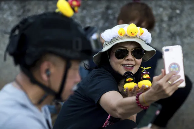 A protester takes a selfie with yellow ducks, which have become good-humored symbols of resistance during anti-government rallies, on Wednesday, November 25, 2020, in Bangkok Thailand. (Photo by Wason Wanichakorn/AP Photo)