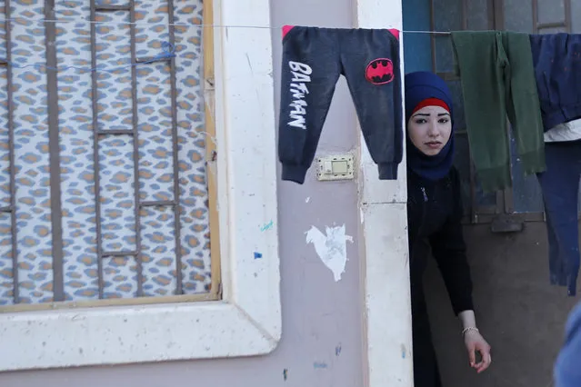 In this Friday, April 13, 2018 photo, a Syrian girl who was displaced with her family from eastern Ghouta looks outside her door at a shelter in the village of Horjelli, in the Damascus countryside, Syria. Thousands of Syrians displaced by the battle for the once-lush suburbs of Damascus now find themselves in a crowded settlement, where for the first time in recent memory they have enough to eat. The community is home to some 18,000 people displaced by the offensive that drove rebels out of eastern Ghouta. On Saturday, the Syrian government announced the capture of Douma, the last rebel stronghold in eastern Ghouta and the site of an alleged chemical attack that prompted a Western missile strike. (Photo by Hassan Ammar/AP Photo)