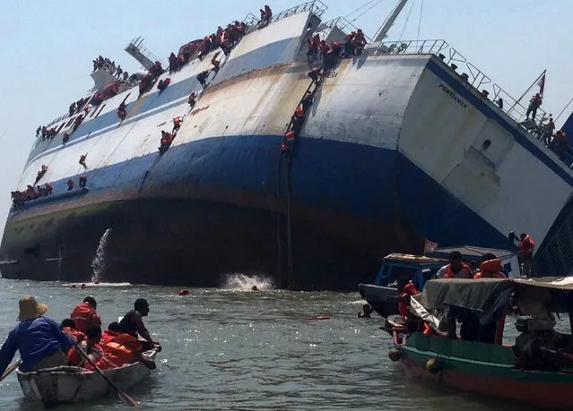 Passengers climb down the side of the ferry KM Wihan Sejahtera as it capsizes in Tanjung Perak port, Surabaya, East Java November 16, 2015 in this photo provided by Antara Foto. The Tanjung Perak harbour master reported that 175 passengers and crew evacuated the ship and there were no casualties. Picture taken November 16, 2015. (Photo by Polair Polda Jatim/Reuters/Antara Foto)
