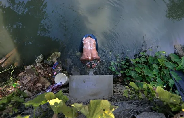 A Sri Lankan man bathes in water flowing from a concrete pipe near a polluted canal on International Day for the Eradication of Poverty in Colombo, Sri Lanka, Monday, October 17, 2016. (Photo by Eranga Jayawardena/AP Photo)
