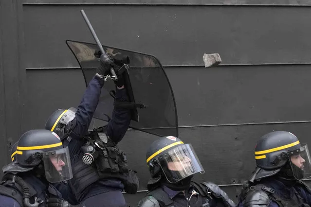A police officer uses his shield to avoid a stone thrown by youths during a demonstration Thursday, April 6, 2023 in Paris. Hundreds of thousands of people are expected to fill the streets of France Thursday for the 11th day of nationwide resistance to a government proposal to raise the retirement age from 62 to 64. The furious public reaction to the plan has cornered and weakened French President Emmanuel Macron. (Photo by Christophe Ena/AP Photo)