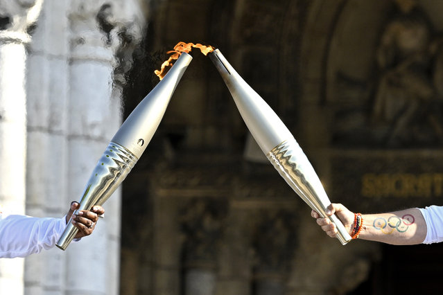 Claudia Tagbo, French-Ivorian actress and comedian and Pascal Touitou carry the Olympic Torch at Basilique du Sacre-Coeur de Montmartre during the second day of the Paris 2024 Olympic Torch Relay on July 15, 2024 in Paris, France. (Photo by Kristy Sparow/Getty Images)