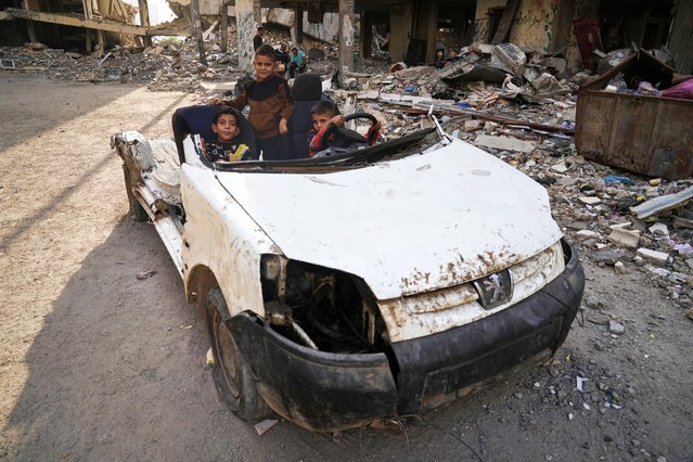 Palestinian children play in a destroyed car in Gaza City, November 24, 2025. (Photo by Jehad Alshrafi/AP Photo)