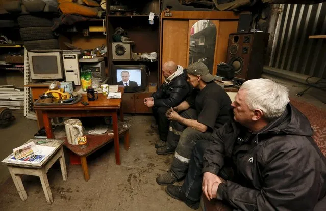 Workers watch a television broadcast of Russian President Vladimir Putin address to the Federal Assembly at an auto repair shop in the Siberian town of Divnogorsk near Krasnoyarsk, Russia, December 3, 2015. Putin used his annual state of the nation speech on Thursday to warn Turkey the Kremlin planned to adopt further sanctions against it to punish Ankara for shooting down a Russian warplane near the Syrian-Turkish border last week. (Photo by Ilya Naymushin/Reuters)